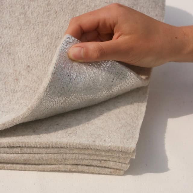 Hand holding thick layers of non-toxic radiant wool felt insulation designed for 4-season yurts.